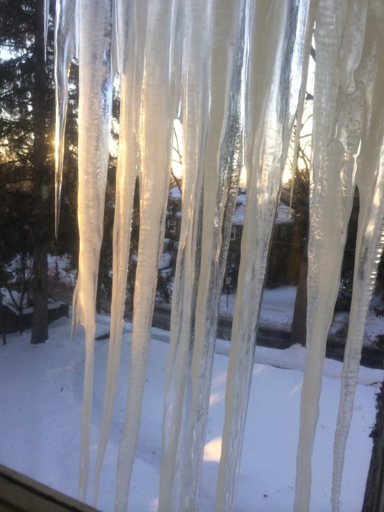 Setting sun gilds the icicles hanging outside the bathroom window.